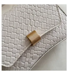 Detailed close-up of woven white leather bag with gold cylindrical metal lock