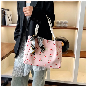 Detailed close-up of pink corduroy tote bag with cherry print and white woven handle