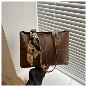 Detail of a brown patchwork tote bag with snake skin texture and vintage silk scarf