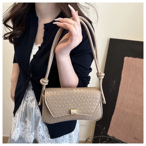 Detail of beige woven underarm bag featuring a golden metal buckle and knot strap