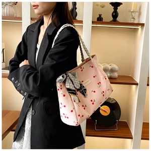 Detail of pink corduroy tote bag with cherry print and decorative ribbon handles