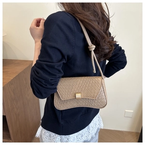 Detail of the woven texture and golden metal buckle on a beige underarm shoulder bag