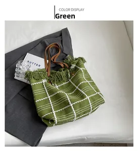 Detail of green plaid woven tote bag with fringe edge and brown leather handles