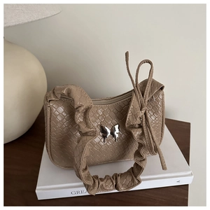Détail du sac hobo tissé beige avoine avec boucle papillon argentée et poignée plissée