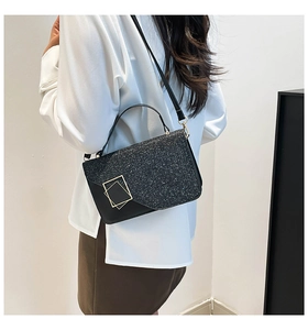 Detail van zwarte crossbodytas met lovertjes en gouden sluiting gedragen door een model