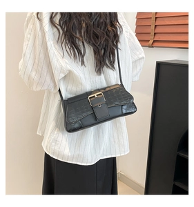 Detail of black baguette bag showing croc-embossed flap and gold buckle closure