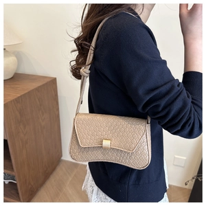 Detail of beige faux crocodile leather shoulder bag with gold square buckle and knotted strap