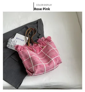 Detail of rose pink checkered woven tote bag with fringe accents and leather straps