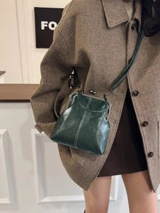 Detail of dark green vintage frame bag with white stitching and metal ball clasp
