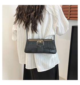 Detail showing crocodile texture on black underarm bag with a large gold metal buckle