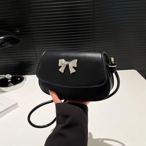 Macro shot of black matte leather saddle bag with silver metal bow clasp and strap detail