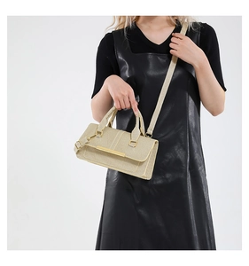 Detail of light gold woven shoulder bag with metallic trim and detachable strap