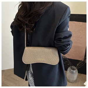 Close-up of beige woven texture handbag with gold fashion lettering on a model