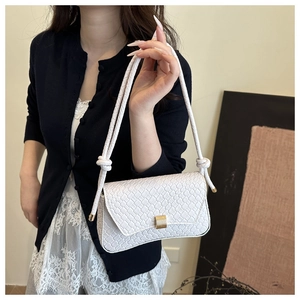 Detail view of white woven shoulder bag featuring a gold buckle and braided dual straps