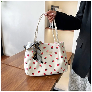 Detail of white corduroy tote bag with strawberry prints and decorative silk scarf handles