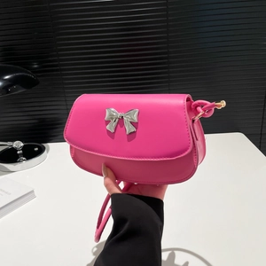 Detail of hot pink crossbody bag with metallic silver bow and smooth leather texture