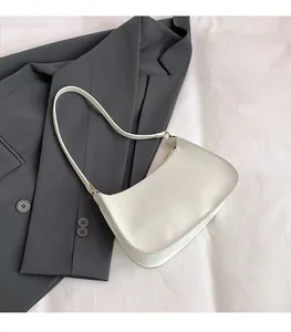 Close-up of white half-moon underarm bag placed on a grey blazer showing smooth PU texture