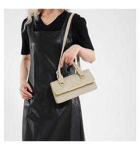 Detail of woven texture handbag with golden metal hardware on a cross-body bag