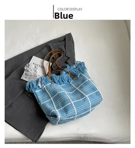 Detail view of light blue woven tote bag featuring white grid lines and fringe trim