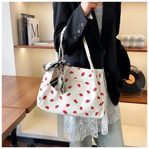Close-up of white corduroy tote bag with strawberry print and silk scarf on strap