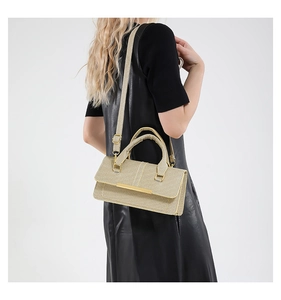 Detail view of champagne glitter crossbody bag with gold metal trim on black leather outfit
