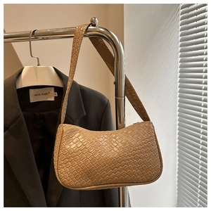 Detail of light khaki woven texture and moon shape design on minimalist shoulder bag