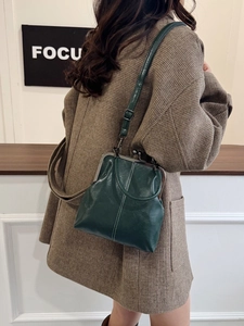 Detail of vintage dark green kiss-lock handbag with white stitching and leather texture