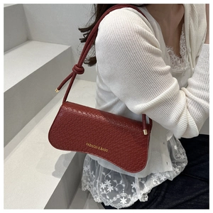 Close-up of wine red faux crocodile leather texture and stylish shoulder strap knot detail