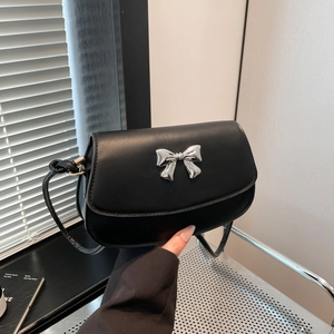 Detail of a black semi-circle flap bag featuring a silver metal bow buckle decoration
