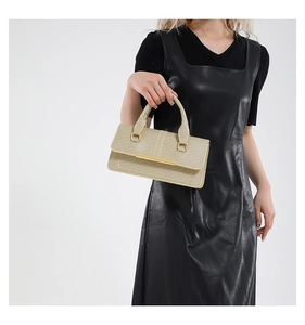 Detail of champagne gold textured handbag with long metallic buckle for evening occasions