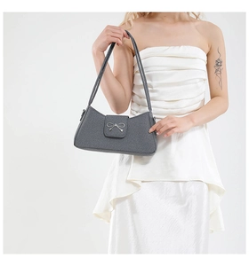 Détail du sac baguette gris avec un nœud en métal argenté et une texture tissée