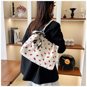 Detail of strawberry print corduroy tote bag with fashion tag and silk scarf handle
