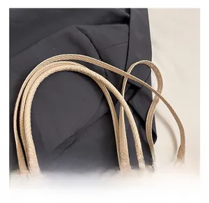 Macro detail of the woven texture and soft handles on a beige pillow shoulder bag