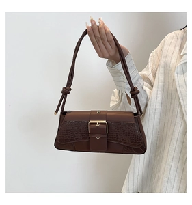 Detail of brown faux crocodile leather shoulder bag with gold buckle and knotted strap