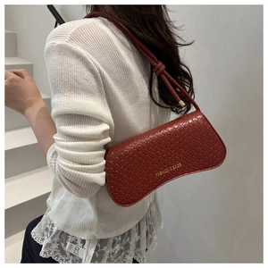 Detail of red woven texture handbag with golden text logo held by a model
