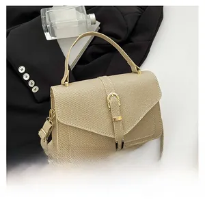 Detail view of beige textured small square bag featuring gold buckle belt and top handle