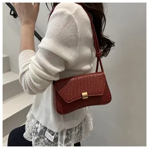 Detail of reddish-brown woven texture shoulder bag with gold metal clasp and knot strap