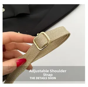 Close-up of the beige woven adjustable shoulder strap with a gold rectangular metal buckle