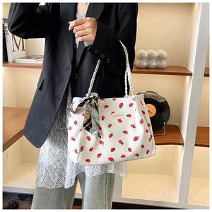 Detail of white corduroy tote bag with strawberry print and decorative patterned silk scarf