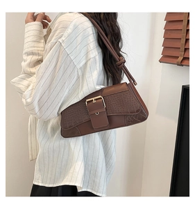 Detailed view of brown leather shoulder bag with faux crocodile pattern and gold buckle