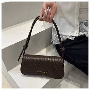 Close-up of dark brown woven texture bag with gold hardware and knotted strap details
