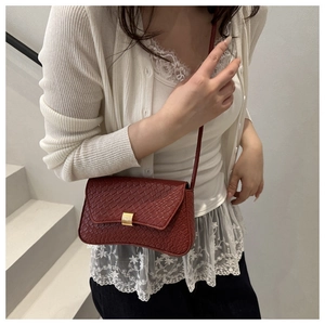 Detail of red croc-embossed leather underarm bag with gold buckle on a model