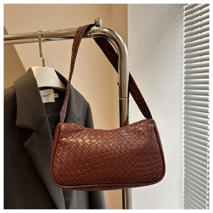 Close-up of brown woven texture on an underarm bag hanging from a metal hanger
