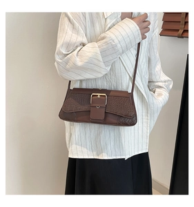 Detail of brown crocodile pattern flap and golden buckle on retro crossbody shoulder bag