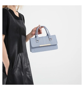 Detail of light blue woven handbag featuring gold metal trim and double handles