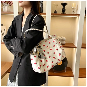 Close-up of white corduroy tote bag with red strawberry embroidery and silk scarf detail