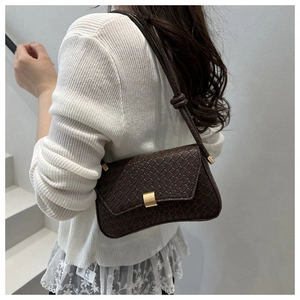 Detail of dark brown woven texture underarm bag with golden buckle and knot strap detail
