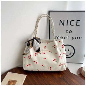 Detail of cream corduroy tote bag with cherry print, woven handles and decorative silk scarf