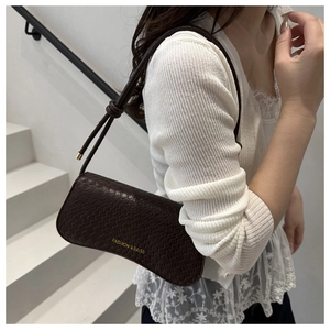 Detail of dark chocolate woven handbag with fashion text and curved bottom design