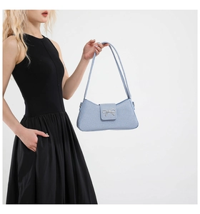 Détail du sac baguette bleu clair en tissu texturé avec boucle nœud argenté sur modèle